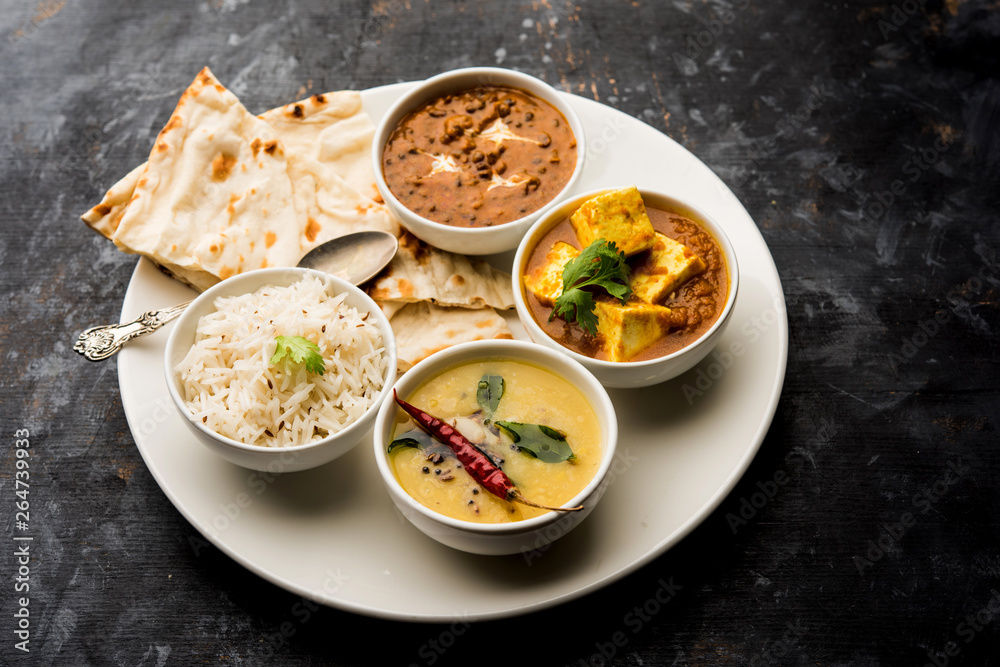 Indian vegetarian platter / Thali having Palak paneer butter masala, dal makhani, flat bread or naan and rice served in a white plate Indian vegetarian platter / Thali having Palak paneer butter masala, dal makhani, flat bread or naan and rice served in a white plate