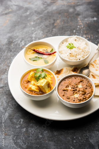 Indian vegetarian  platter / Thali having Palak paneer butter masala, dal makhani, flat bread or naan and rice served in a white plate