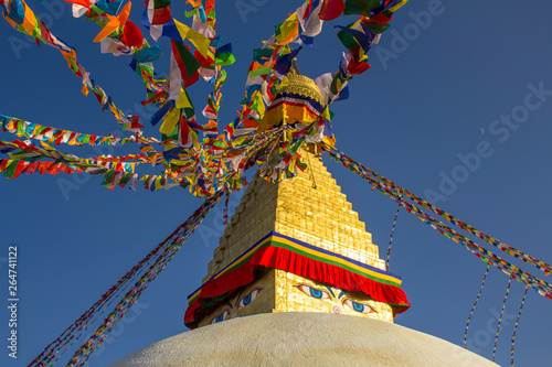 Buddhist Tibetan stupa Bodnath in Kathmandu with multicolored prayer flags against a clean blue sky and the moon