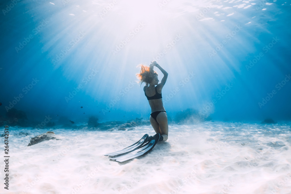 Woman freediver posing over sandy sea with fins. Freediving underwater in Hawaii
