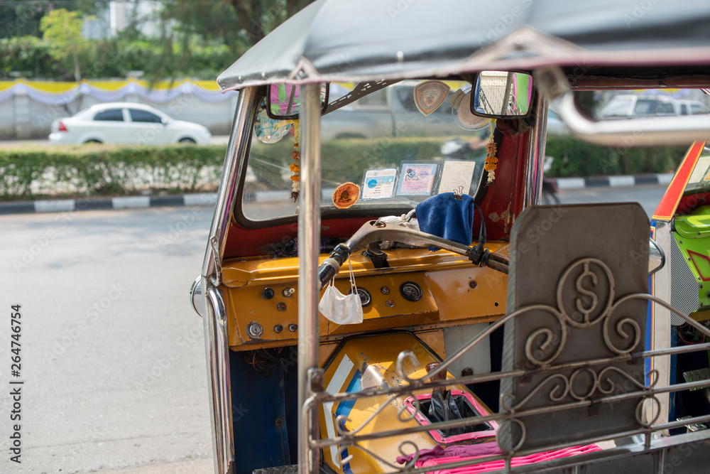 Fototapeta premium Well known and famous local taxi in Thailand, Tuk-Tuk, parking nearby tourist place, waiting for passengers asking for a ride. Image showing lots of details of colourful equipments and elements.