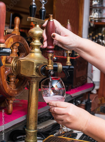 Barman serves the barrel drink. Hand and wine tap.