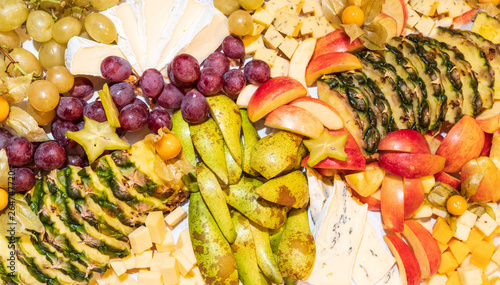 Assortment of raw fruits  berries and brie cheese platter  pineapple  pear  apples  grapes  physalis  carambola healthy food concept background