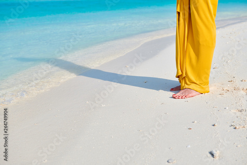 Woman legs in yellow dress on tropical beach