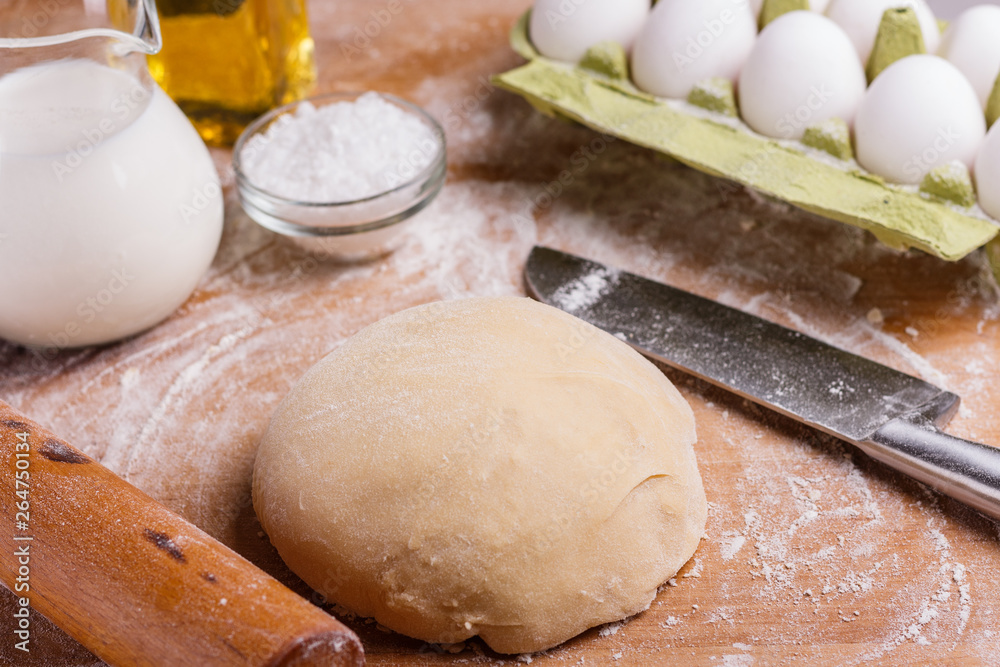 Fototapeta premium young woman in apron kneading dough on board