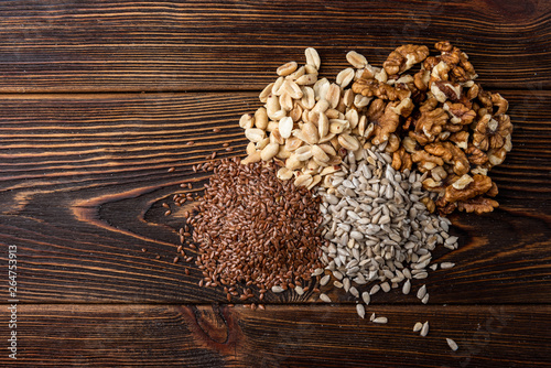 Walnut, peanut, sunflower and flax seeds on dark wooden background.