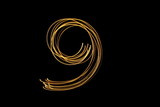 Long exposure, light painting photography. Single number in a vibrant neon metallic yellow gold colour against a black background