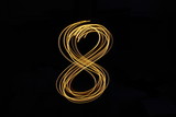 Long exposure, light painting photography.  Single number in a vibrant neon metallic yellow gold colour against a black background