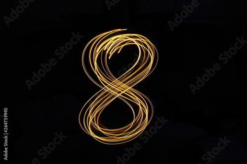 Long exposure, light painting photography.  Single number in a vibrant neon metallic yellow gold colour against a black background photo