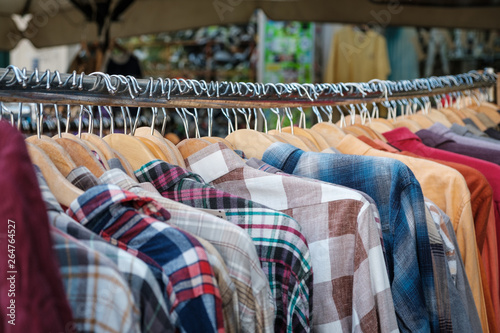 second hand fashion store, closeup of shirts hanging on hangers -