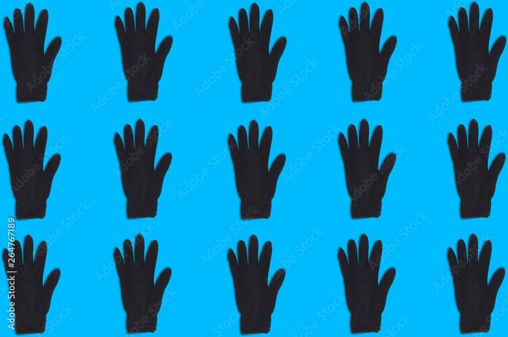 Horizontal rows of black warm woolen gloves on blue background. Seamless pattern. Top view