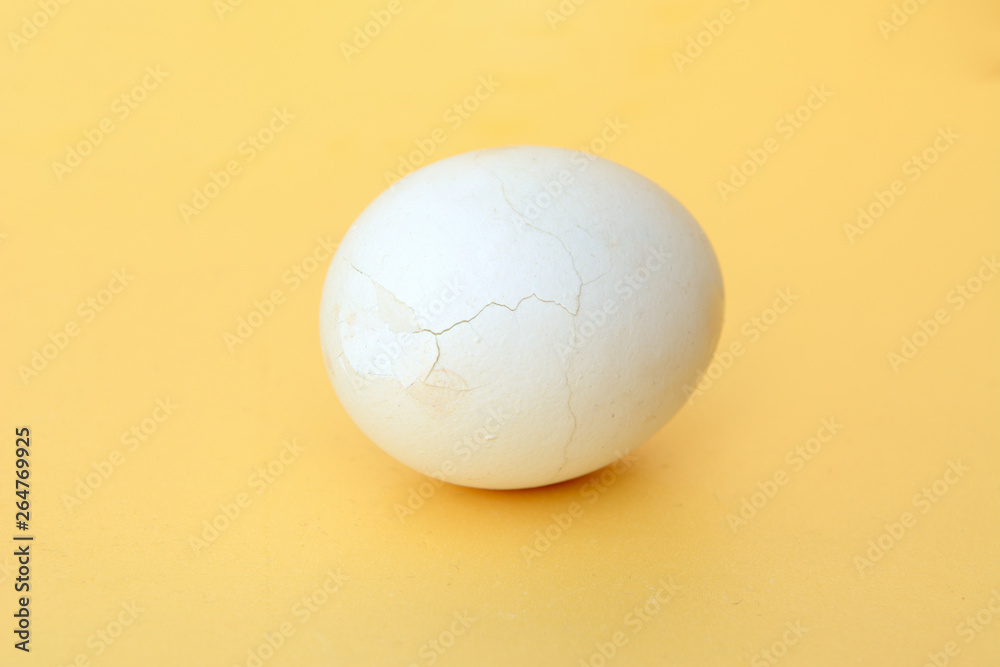 On a yellow background is a white chicken egg with a broken shell. Concept - healthy food