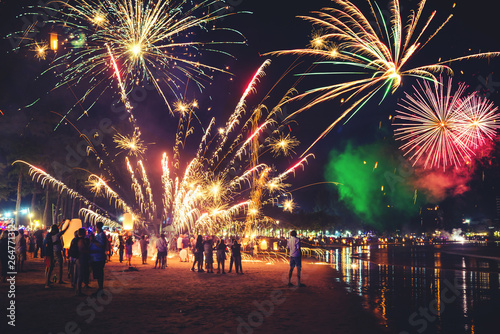 Fireworks with silhouettes of people in a holiday events.New Year fireworks on the beach. Travelers and people celebrate New year day at Kamala Beach Phuket, Thailand.
