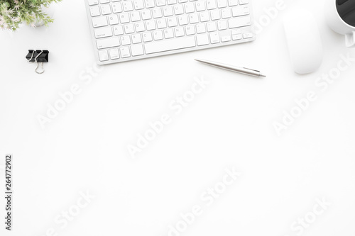 White office desk table with computer mouse, keyboard, cup of coffee and supplies. Top view with copy space, flat lay.