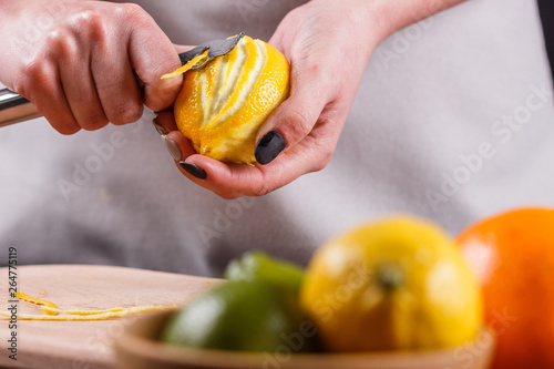 young woman in a gray aprons cuts lemon zest