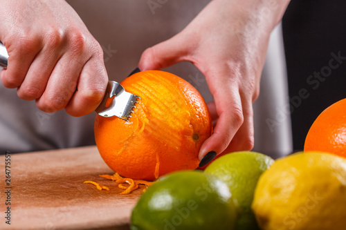 Bilde på lerret young woman in a gray aprons, cuts an orange zest