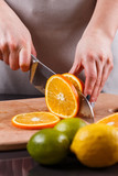 young woman in a gray aprons cuts an orange
