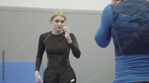 Portrait of female blond trainer teaching unrecognizable athletic man how to do elbow punch in muai thai close up.