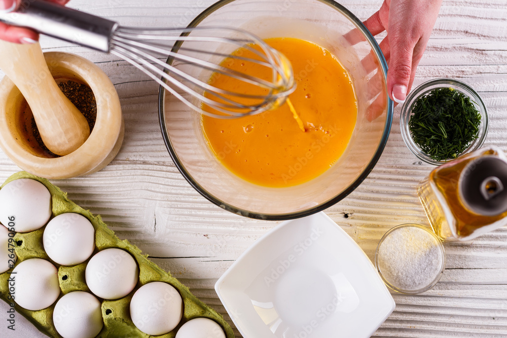 young woman in a gray aprons breaks the eggs young woman in a gray aprons breaks the eggs