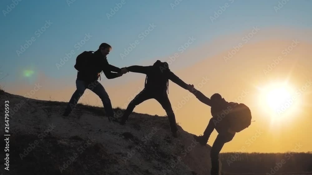 teamwork help lifestyle business travel silhouette concept. group of tourists lends a helping hand climb the cliffs mountains. people climbers climb to the top overcoming hardships the path to victory