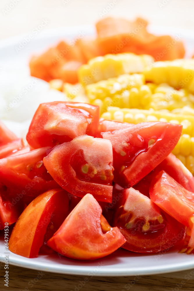 Sliced tomatoes and corn on white plate