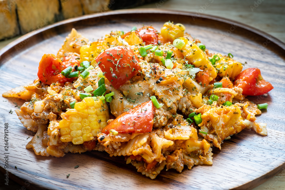 farfalle pasta in tomato sauce with chicken and pork on wooden plate farfalle pasta in tomato sauce with chicken and pork on wooden plate