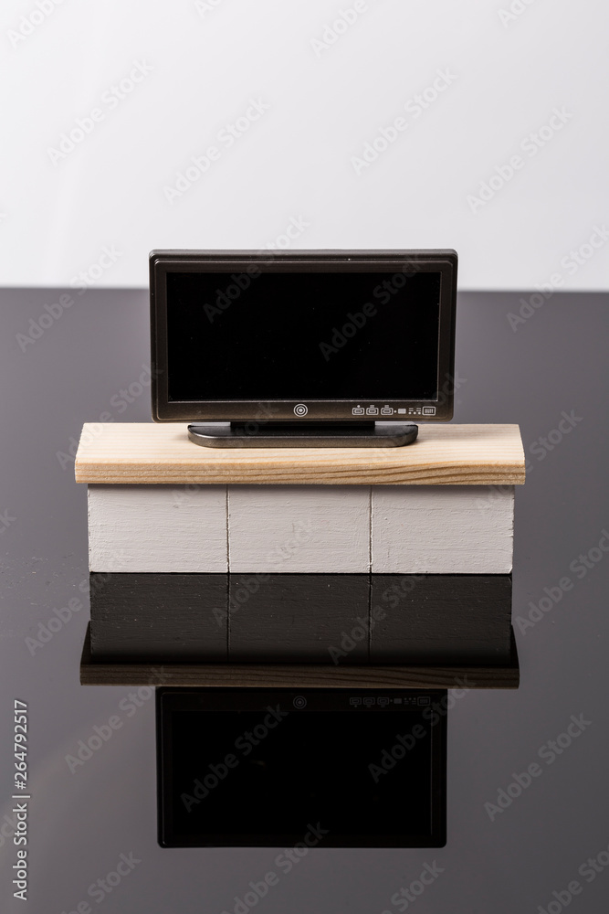 LCD flat tiny toy television on a white furniture over a black and white background LCD flat tiny toy television on a white furniture over a black and white background