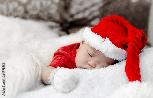 newborn cute baby asian boy in christmas santa costume sleeping on bed