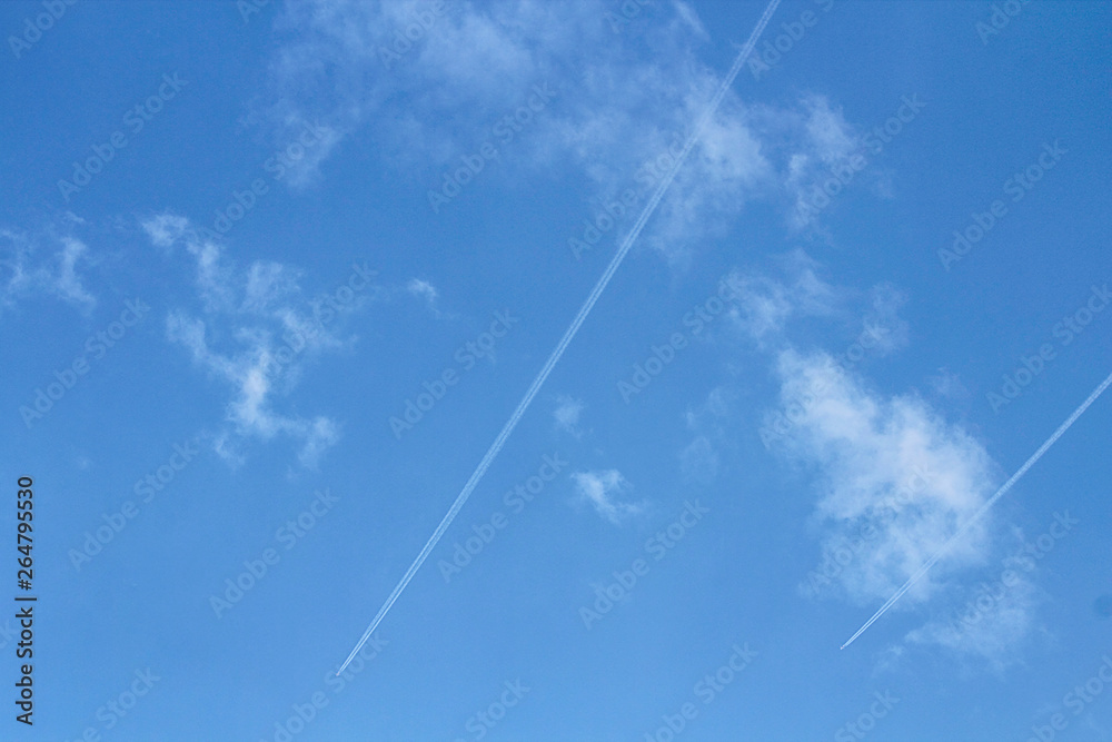 Condensation traces from the aircraft. Blue sky, clouds. Selective focus, place for text.