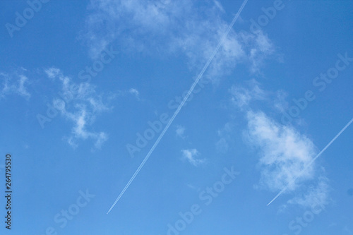Condensation traces from the aircraft. Blue sky, clouds. Selective focus, place for text.