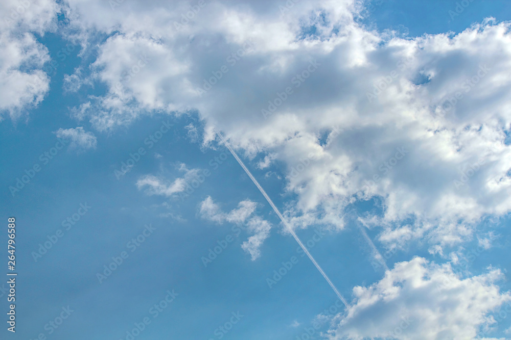 Condensation traces from the aircraft. Blue sky, clouds. Selective focus, place for text. Condensation traces from the aircraft. Blue sky, clouds. Selective focus, place for text.