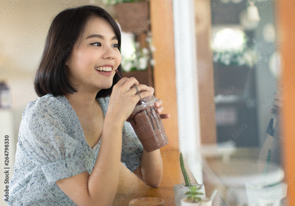 young asian woman short hair in sky dress holding a cup of ice frappe chocolate , young woman smiling