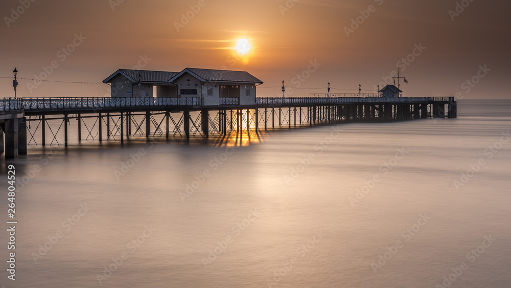 Penarth Pier, on the south Wales coast, near Cardiff, at sunrise. The sky is  orange, and the sea is smooth