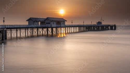 Penarth Pier  on the south Wales coast  near Cardiff  at sunrise. The sky is  orange  and the sea is smooth