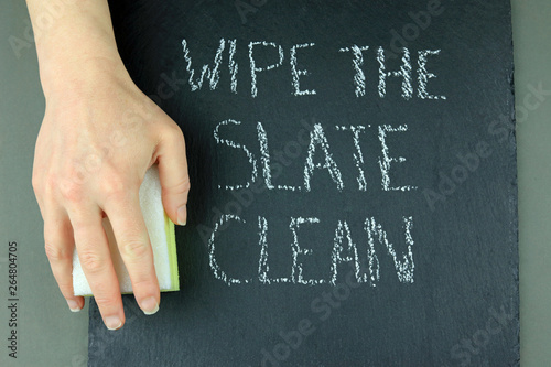 A Hand Holding A Cleaning Sponge Ready To Wipe The Slate Clean