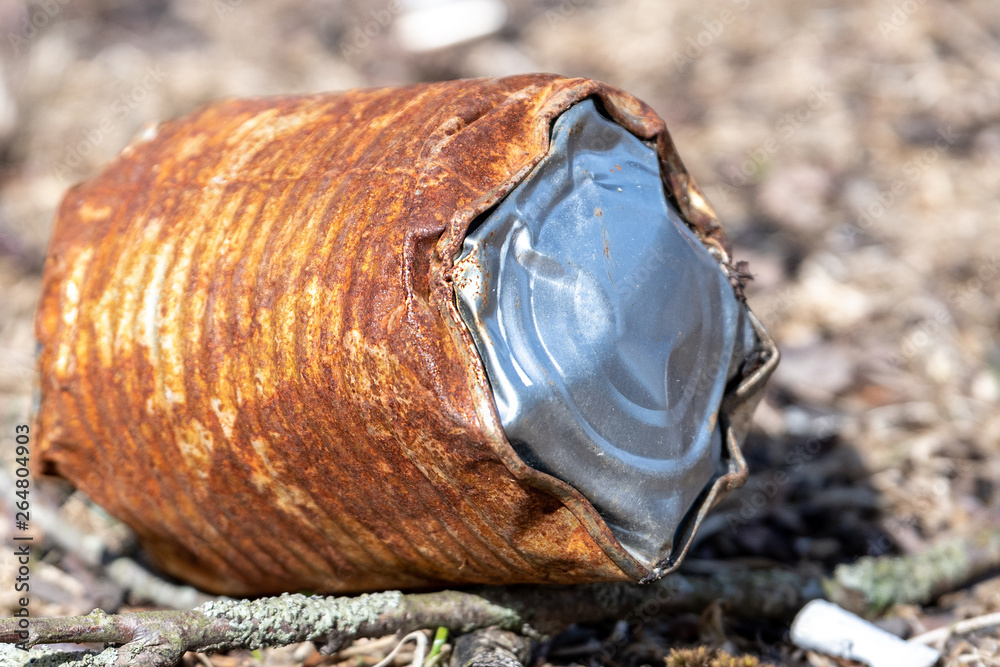 Obraz premium An old, rusted tin can lying on the ground on a sunny day.