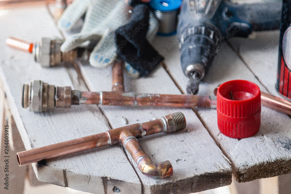 Closeup professional brush for cleaning pipes, fittings, work gloves, copper pipes. Concept installation, plumbing change, solder flux paste, pipeline repair, plumber master, leakage Closeup professional brush for cleaning pipes, fittings, work gloves, copper pipes. Concept installation, plumbing change, solder flux paste, pipeline repair, plumber master, leakage
