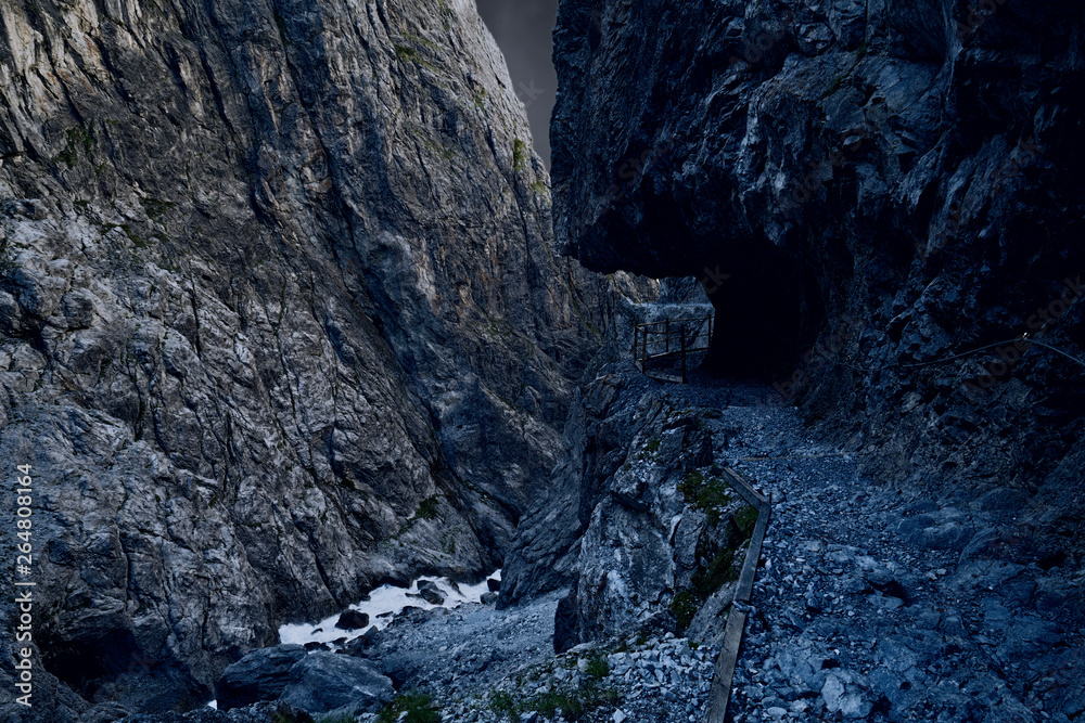 Old narrow mountain path in a canyon, railing on the side, black Old narrow mountain path in a canyon, railing on the side, black