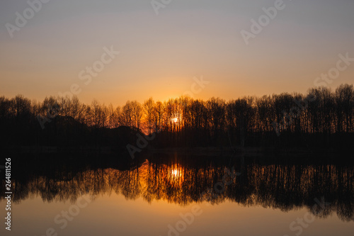 Sunset on the lake. There is a forest in the distance