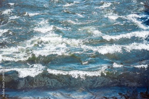 Aqua blue sea waves with white foam on top during a stormy weather – Arial rough splashes of water with bubbles as a background
