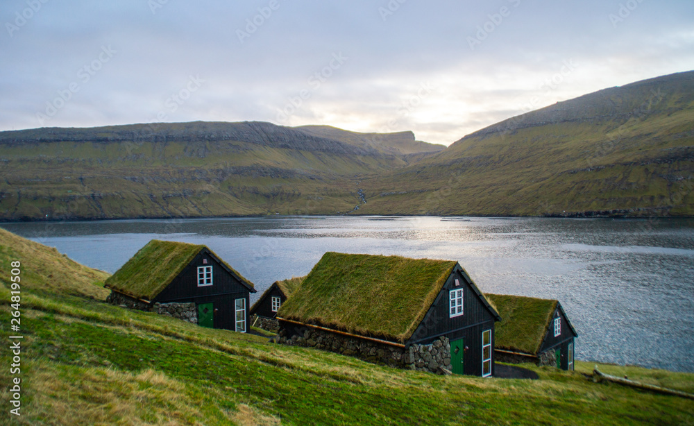 Traditional nordic Scandinavian village houses with green grass roof. Iconic scenic view of Faroe Island, Denmark, Europe. Beautiful tourist spot located at Vágar Island. Moody weather scene. Traditional nordic Scandinavian village houses with green grass roof. Iconic scenic view of Faroe Island, Denmark, Europe. Beautiful tourist spot located at Vágar Island. Moody weather scene.