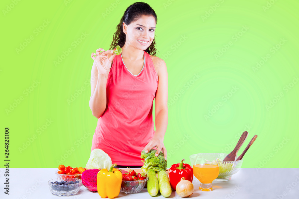 Indian woman holding fresh broccoli on studio Indian woman holding fresh broccoli on studio