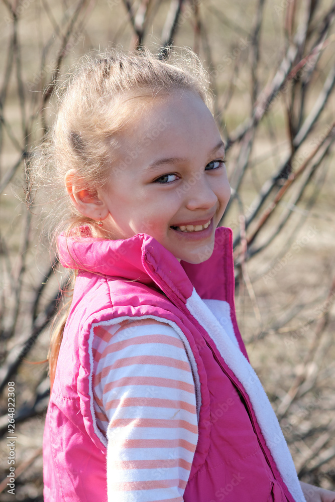 Portrait of a girl in a red vest in early spring on the background of willow Portrait of a girl in a red vest in early spring on the background of willow