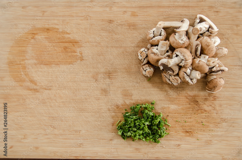 Parsley and mushroom on wooden table, cut and ready to be cooked. Top view in kitchen Parsley and mushroom on wooden table, cut and ready to be cooked. Top view in kitchen