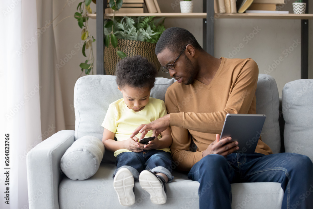 African father helping little son explain new app or game