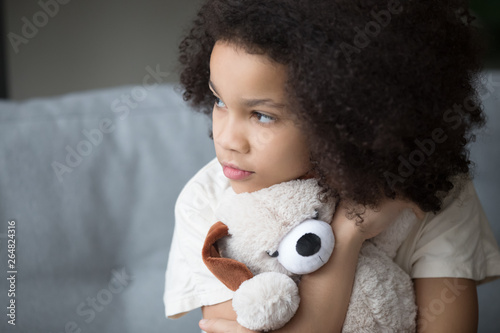 Canvas-taulu Unfortunate stray biracial kid girl embrace stuffed toy looking aside