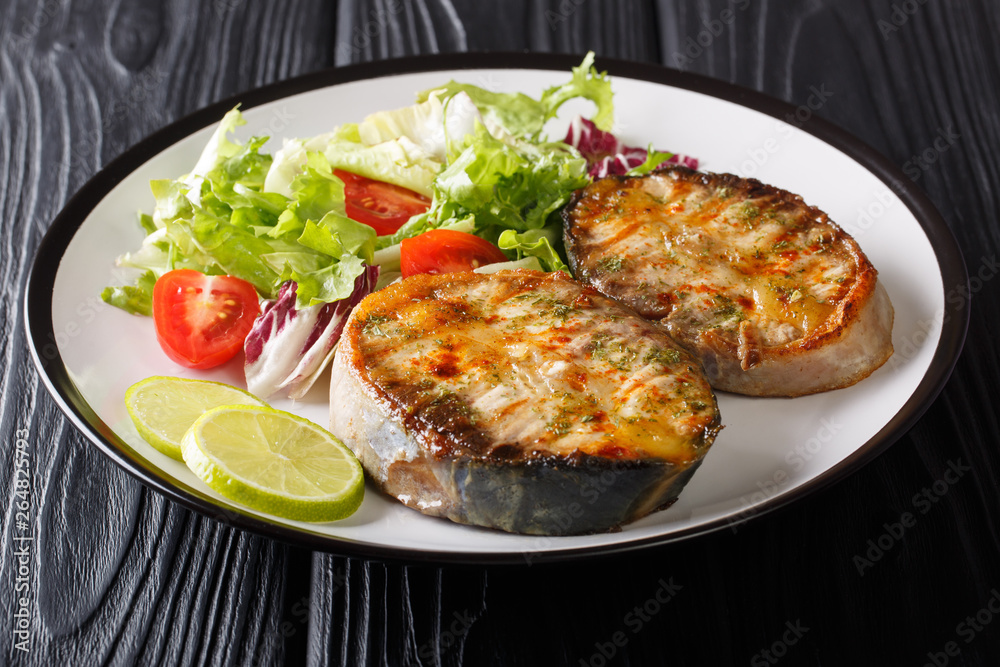 Healthy food fried sturgeon steaks served with fresh vegetable salad close-up on a plate. horizontal
