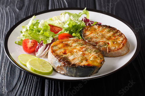 Healthy food fried sturgeon steaks served with fresh vegetable salad close-up on a plate. horizontal