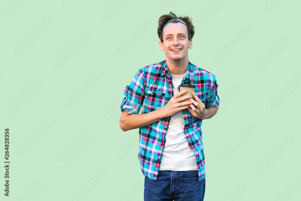 No life without coffee. Handsome young adult hipster man in white t-shirt and checkered shirt holding paper cup with morning coffee and showing love and press to heart. Indoor, isolated, studio shot No life without coffee. Handsome young adult hipster man in white t-shirt and checkered shirt holding paper cup with morning coffee and showing love and press to heart. Indoor, isolated, studio shot