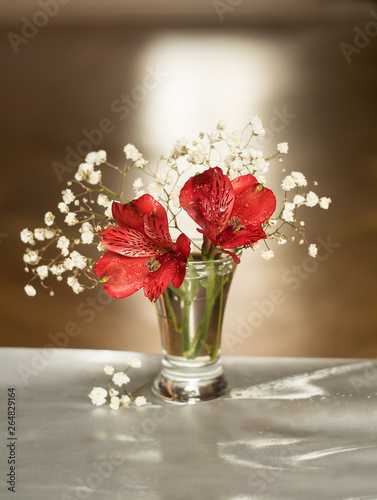 Still life of white and red flowers in a vase on a brown and gray background